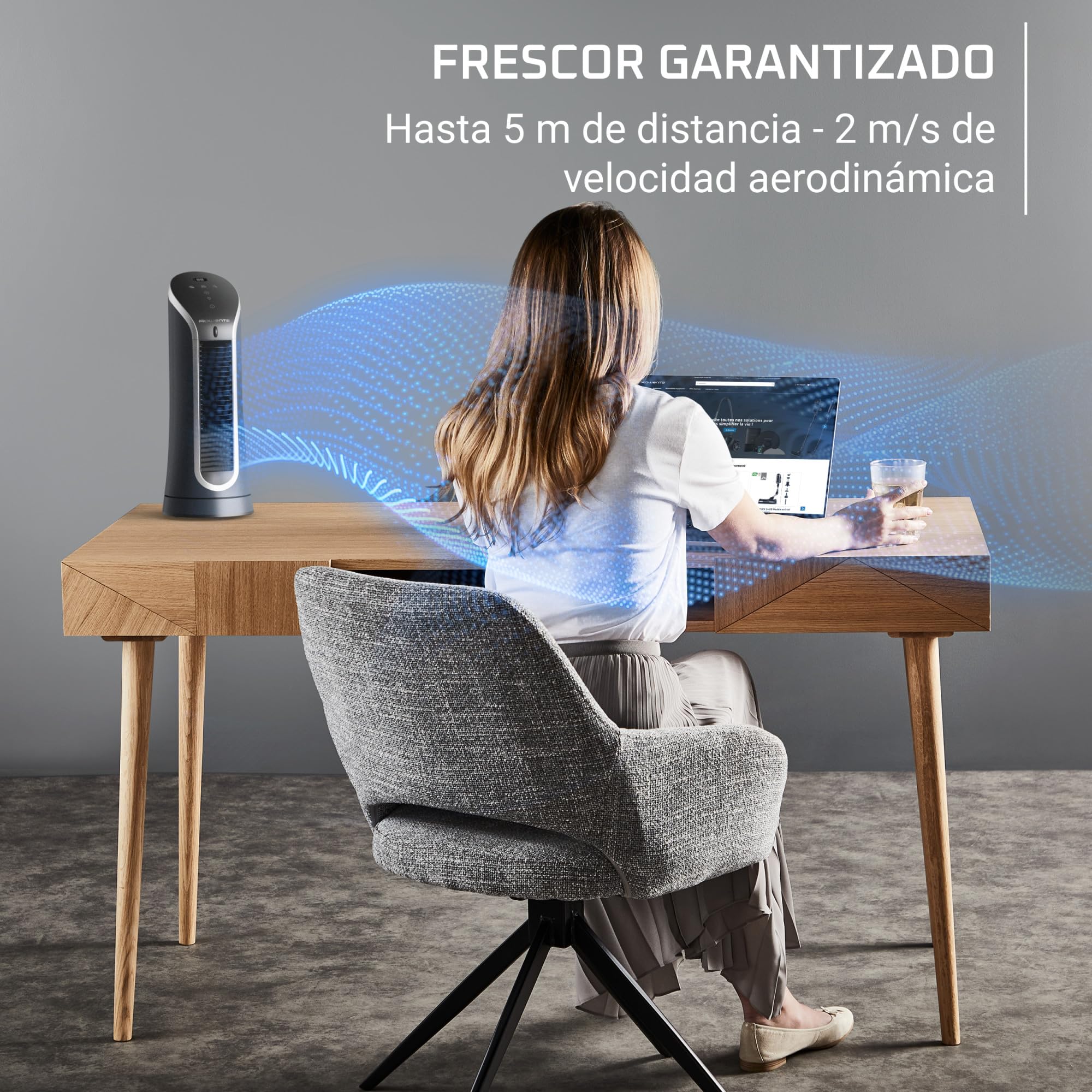 Mujer en escritorio con ventilador Rowenta que proporciona aire fresco hasta 5 metros.