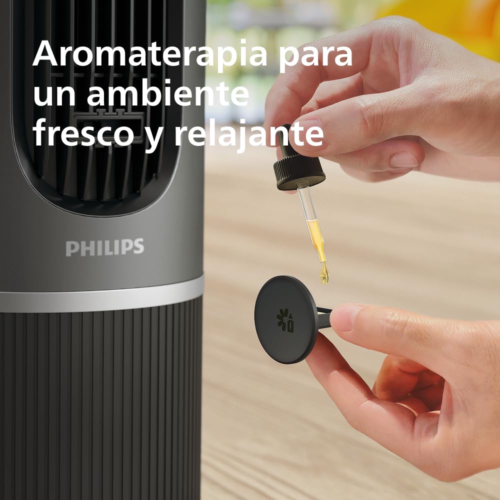 Una mano añade aceite esencial al ventilador de torre Philips para una aromaterapia fresca y relajante.