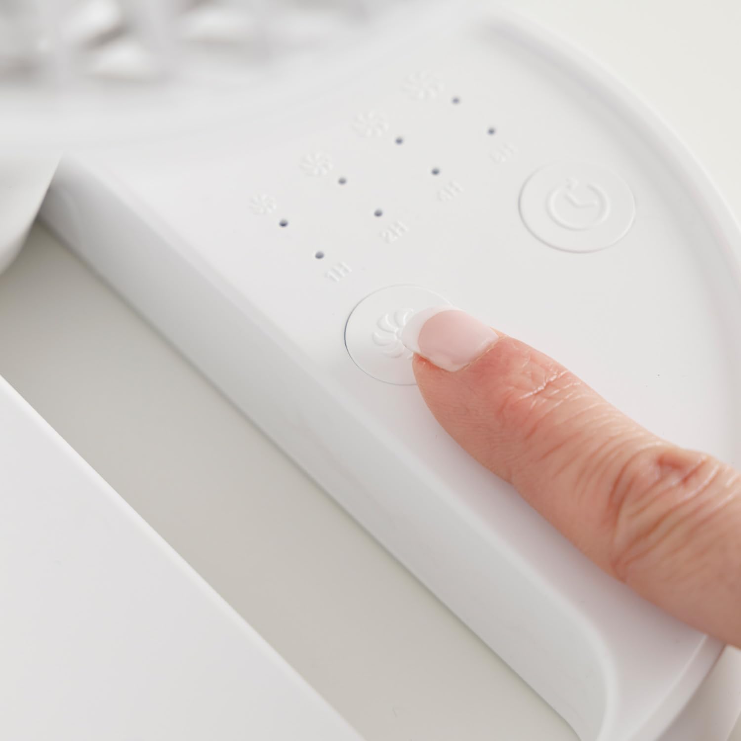 Dedo presionando botón de control en ventilador portátil blanco.