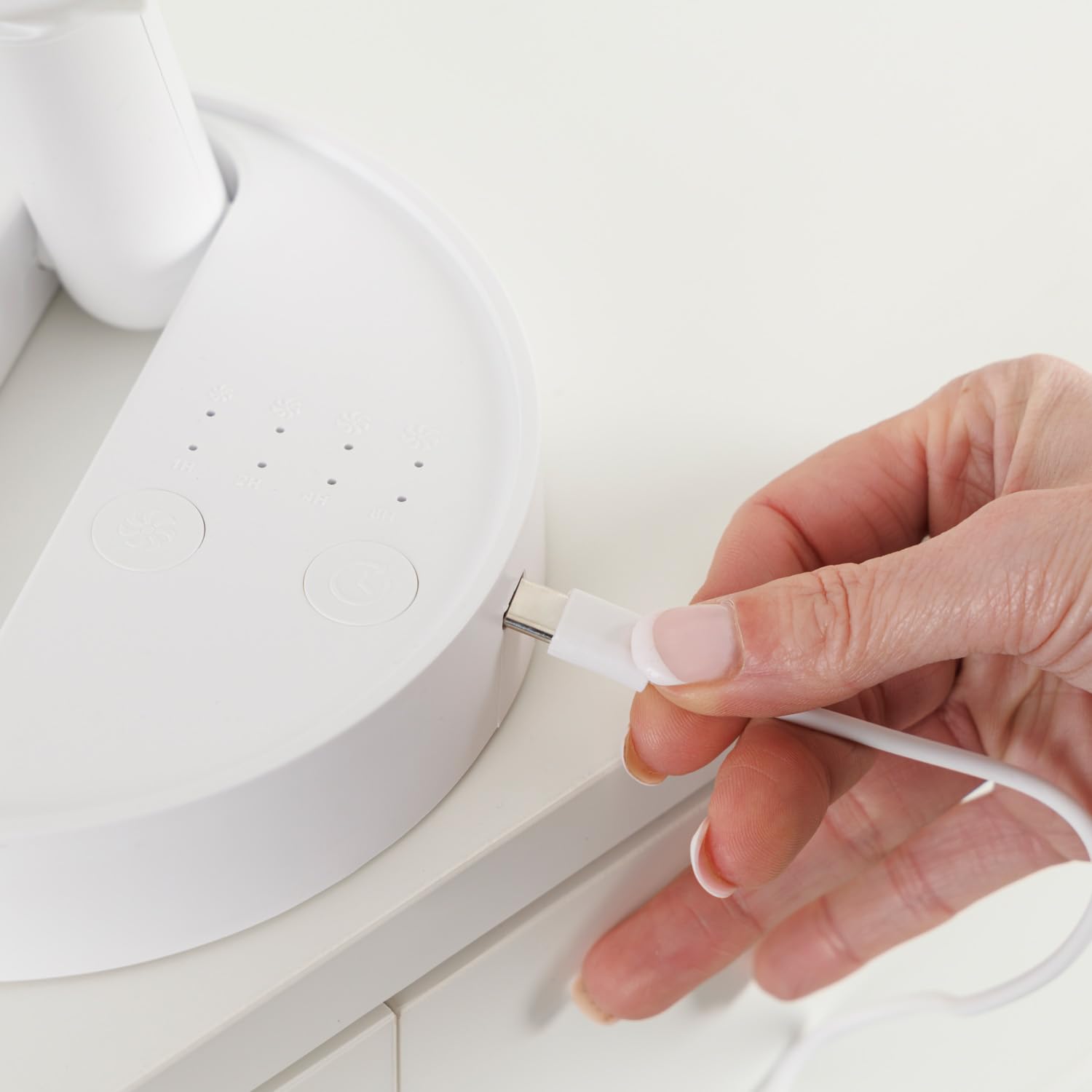 Mano conectando cable USB-C a ventilador portátil compacto blanco