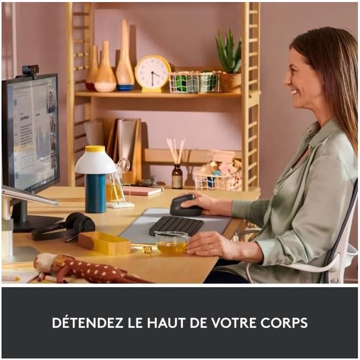 Mujer trabajando felizmente con un ratón ergonómico Logitech Lift en un escritorio ordenado.
