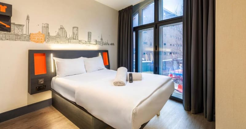 A room at easyHotel Birmingham with its Birmingham-skyline mural and arched window