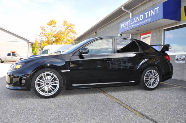 Black Subaru WRX STI sedan with tinted windows outside shop