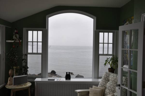 Coastal home sunroom windows overlooking gray ocean view