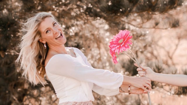 Emyrald Sinclaire — Woman with pink gerbera flower outdoors