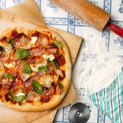 Pizza mit Cherrytomaten, Speck und Sauerrahm