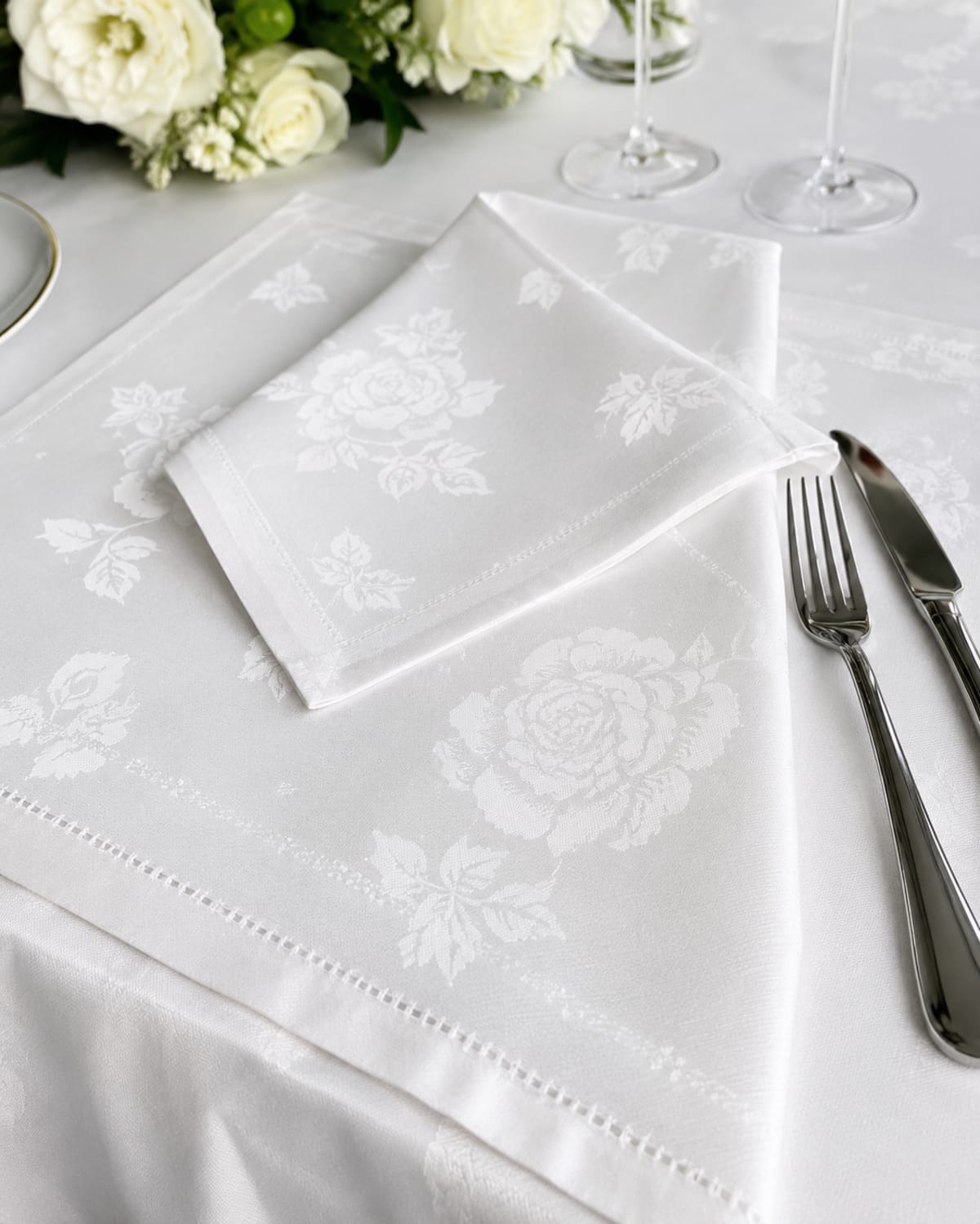 White rose-damask napkin on a matching tablecloth