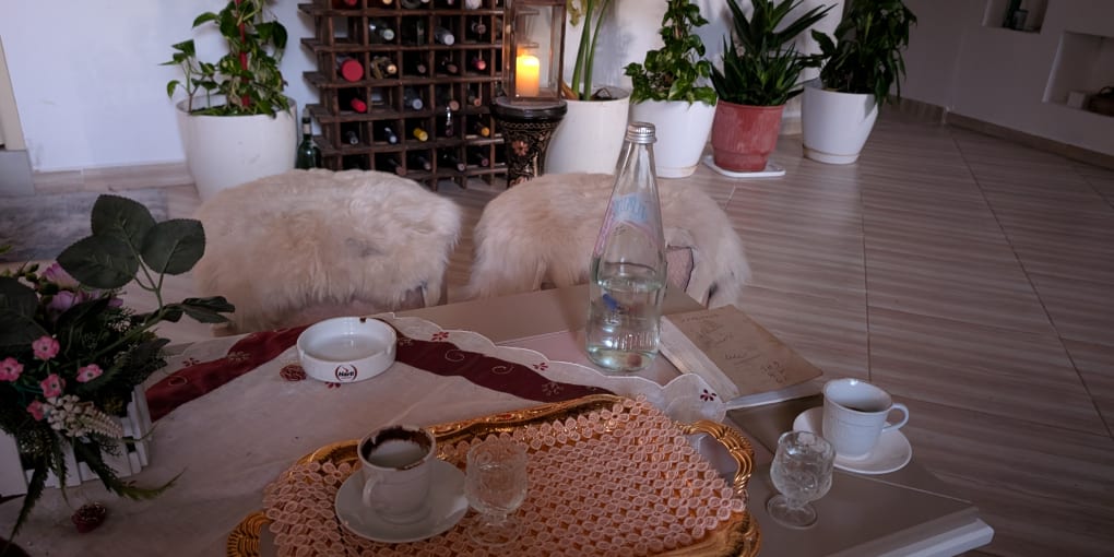 Inside of a home in Albania. Cups of coffee and glasses of Raki sit on a coffee table.