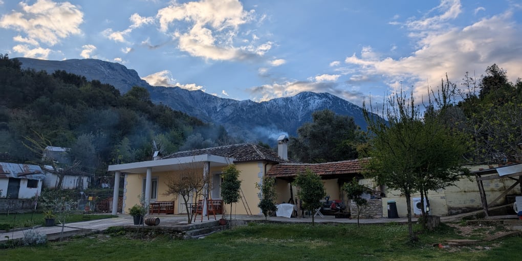A yellow farmhouse in Dukat, Albania on a cold morning. Smoke rises from the chimney, Maja Paliskës is in the background.