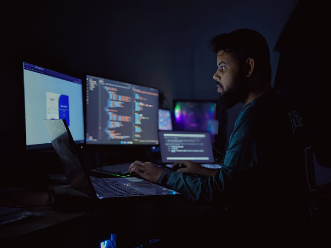 A programmer working at a desk with code on the screen