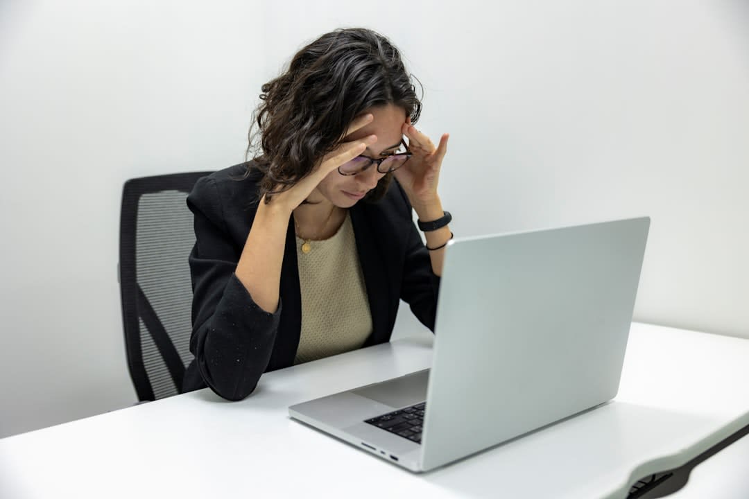 A frustrated professional looking at a computer, symbolizing common mistakes in cold emailing.