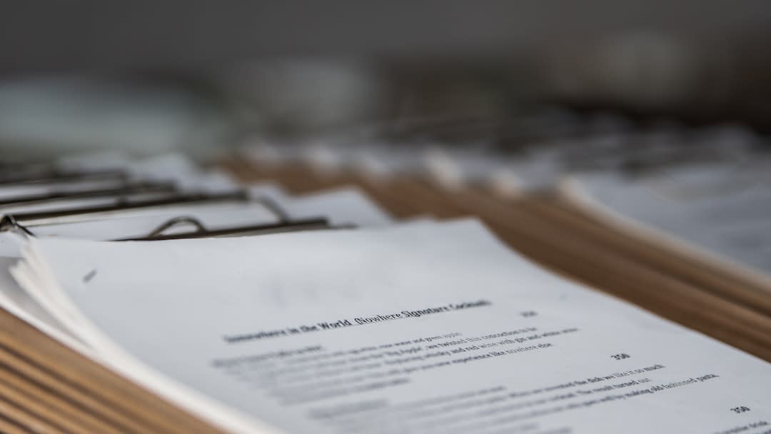 Close-up of hands reviewing cybersecurity compliance documents and regulations