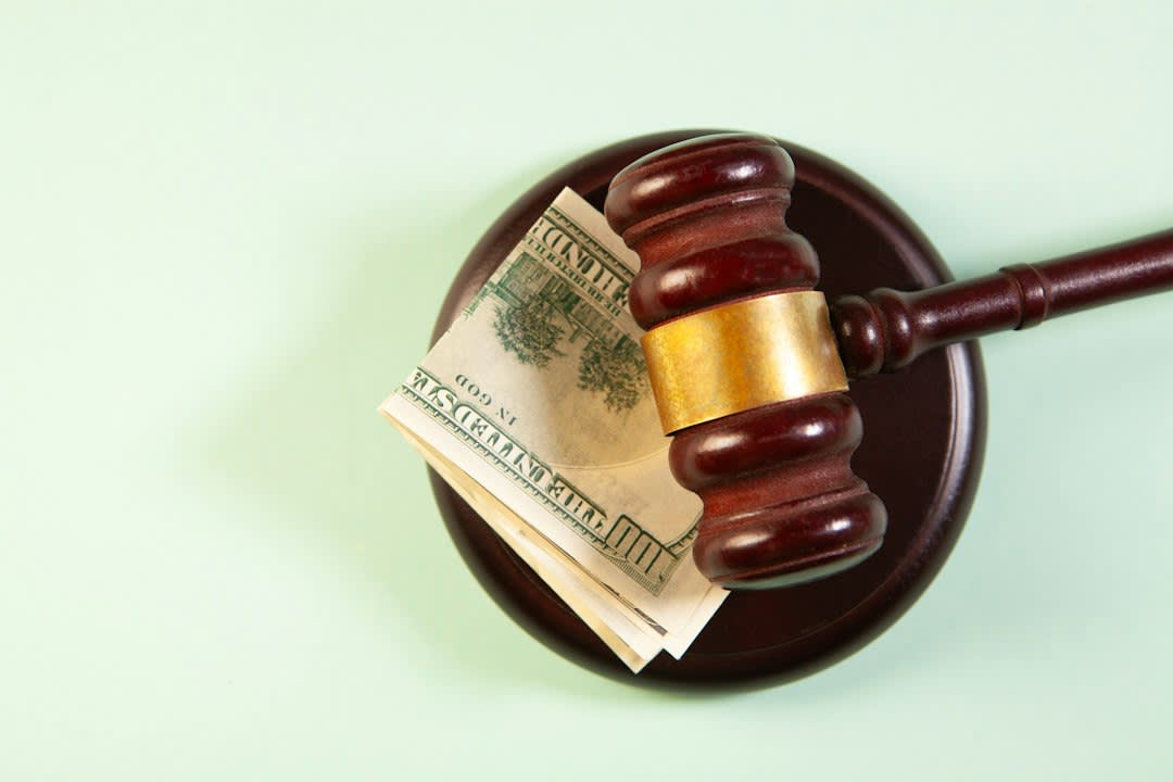 A gavel with currency representing legal fines in technology