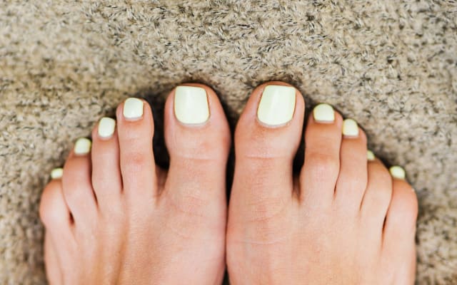 Pedicura con esmalte blanco y detalles dorados