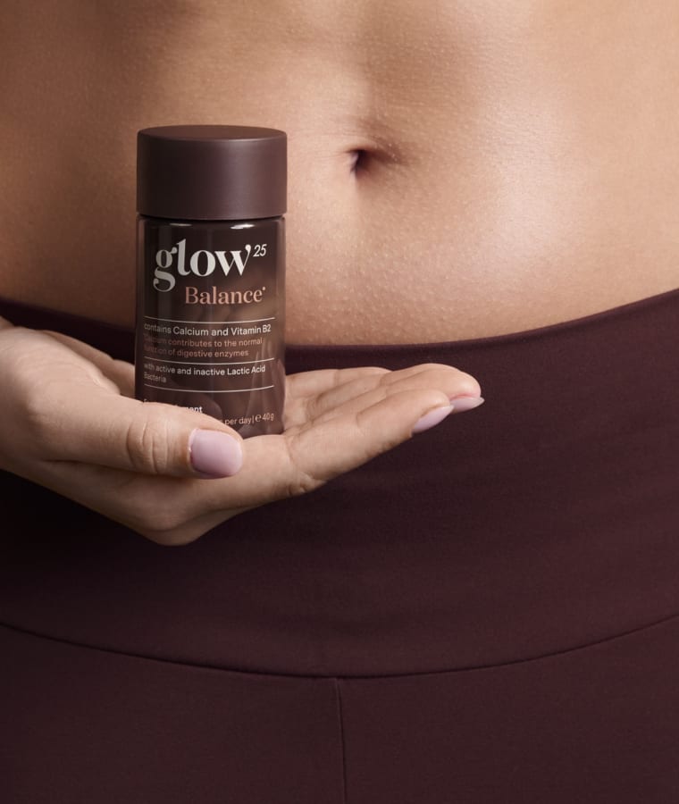Gros plan d'une femme tenant son pot Glow25 Balance — contient du calcium et de la vitamine B2, avec des ferments lactiques actifs et inactifs