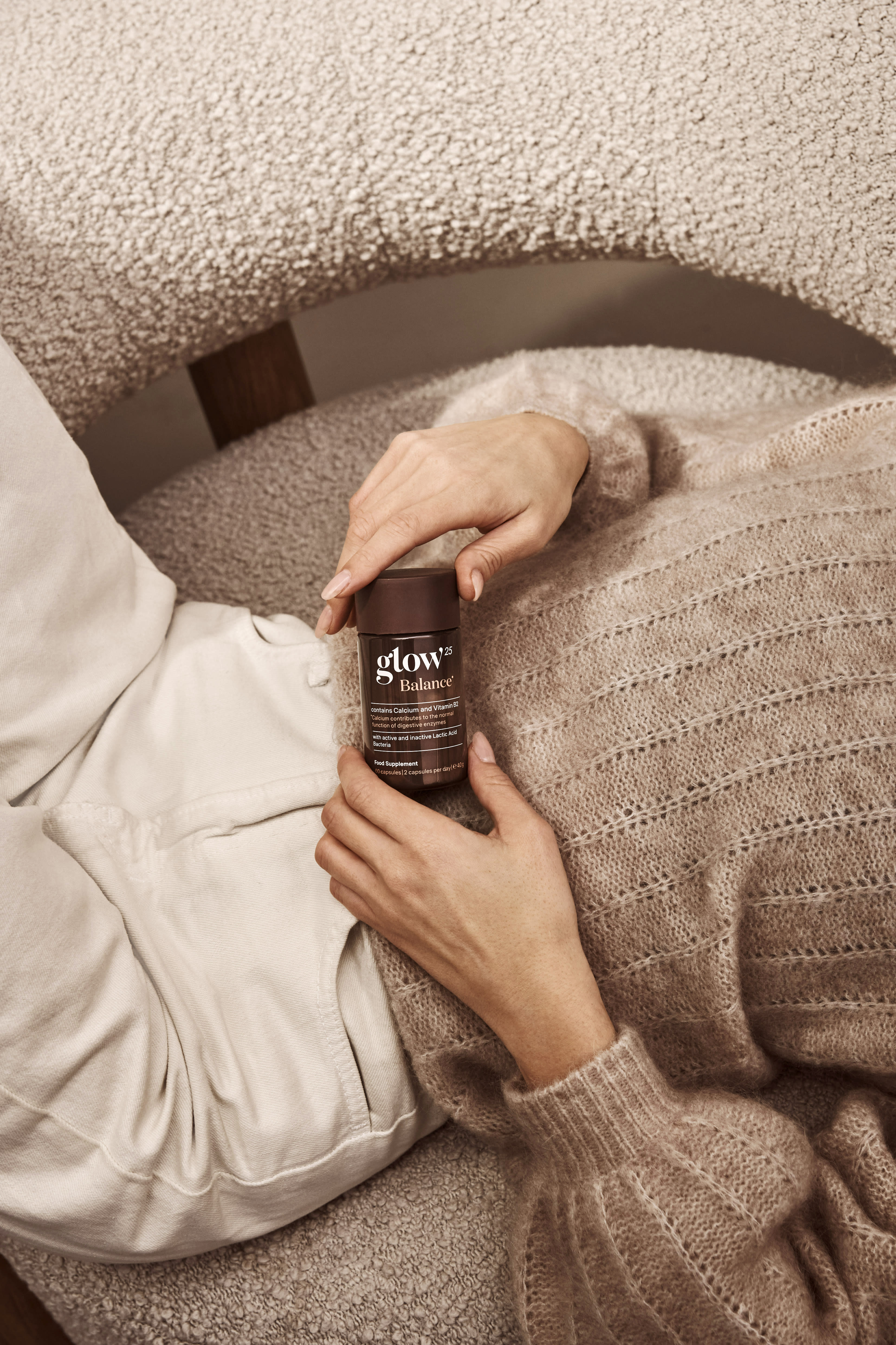 Femme détendue en maille douce, tenant son pot Glow25 Balance