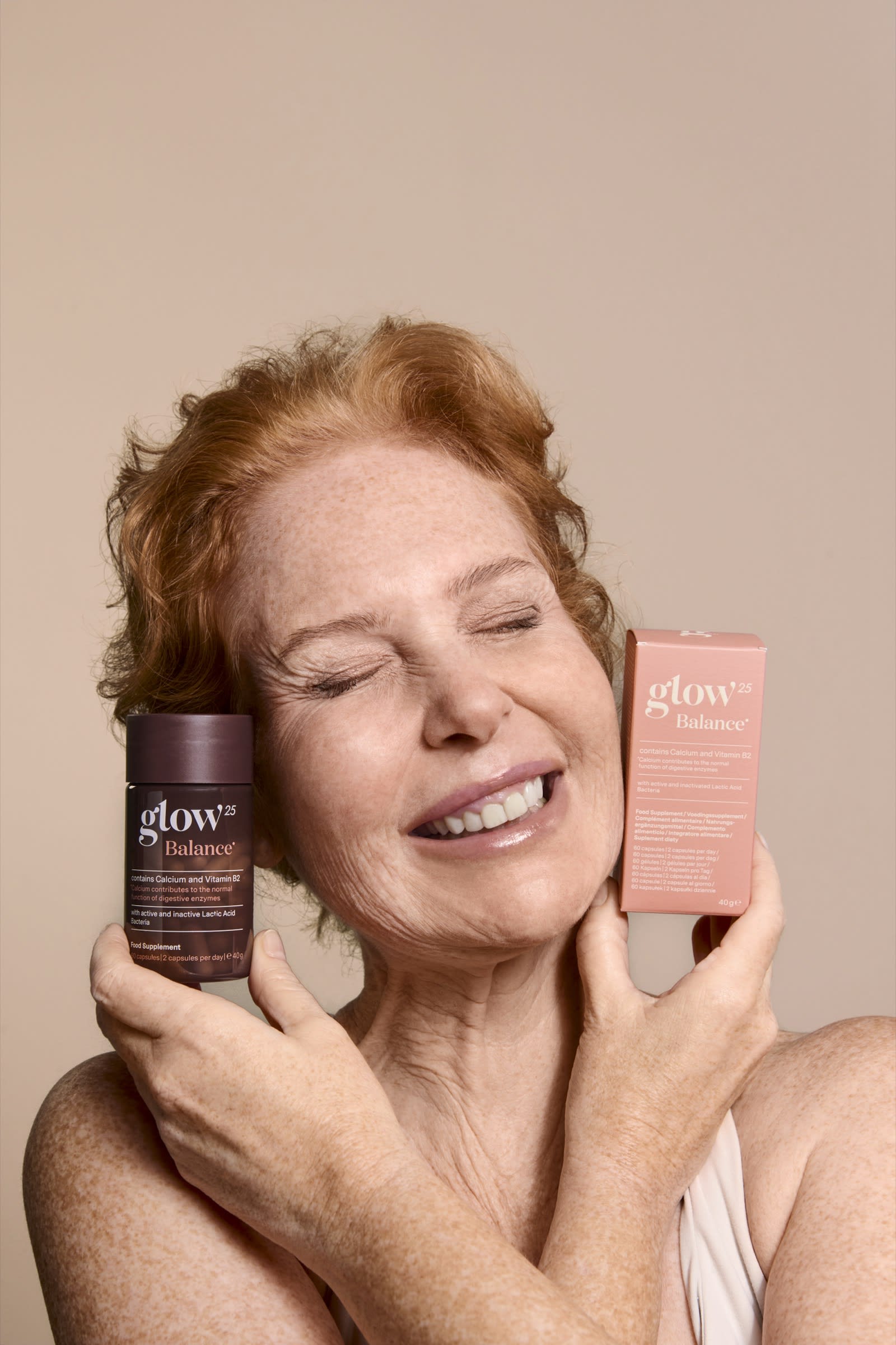 Une femme souriante tenant son pot et sa boîte Glow25 Balance tout près