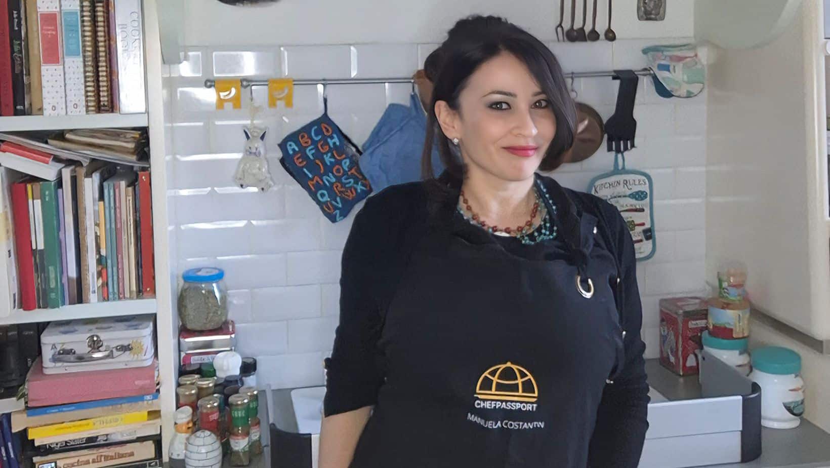 Chef Manuela Costantin in black chef coat standing in her kitchen