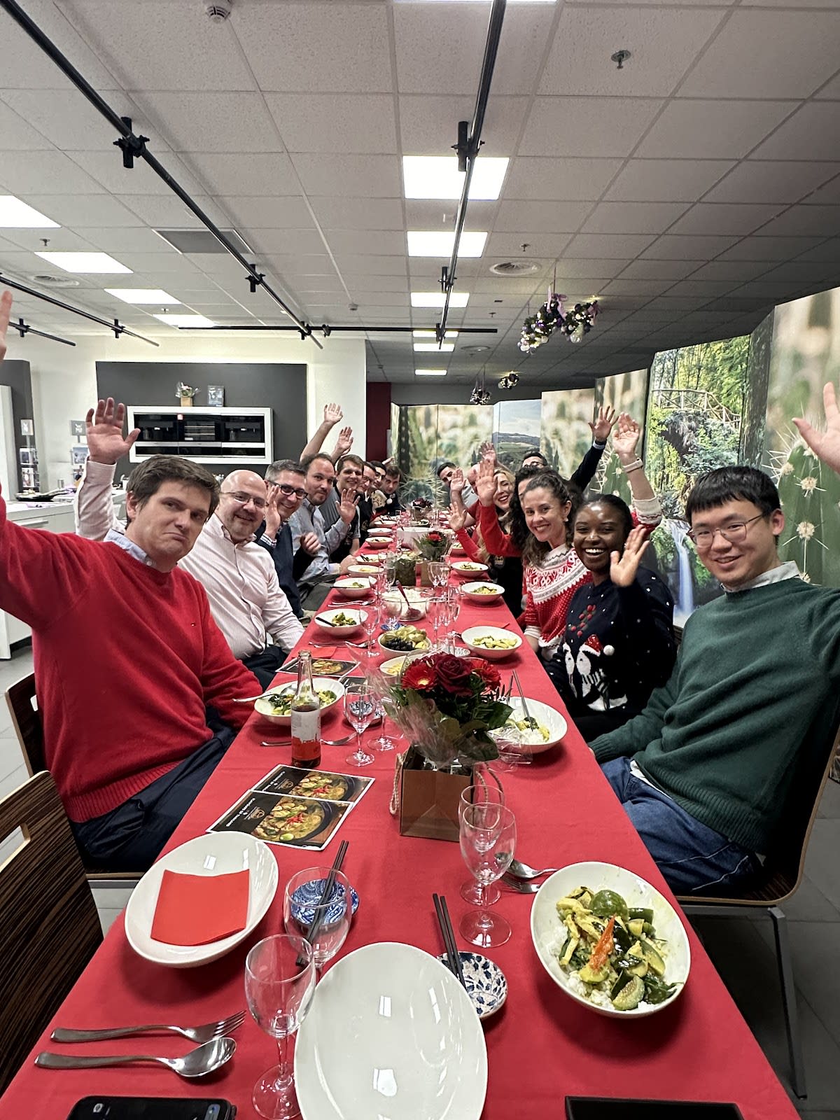 Large corporate team celebrating at festive holiday dinner with raised hands