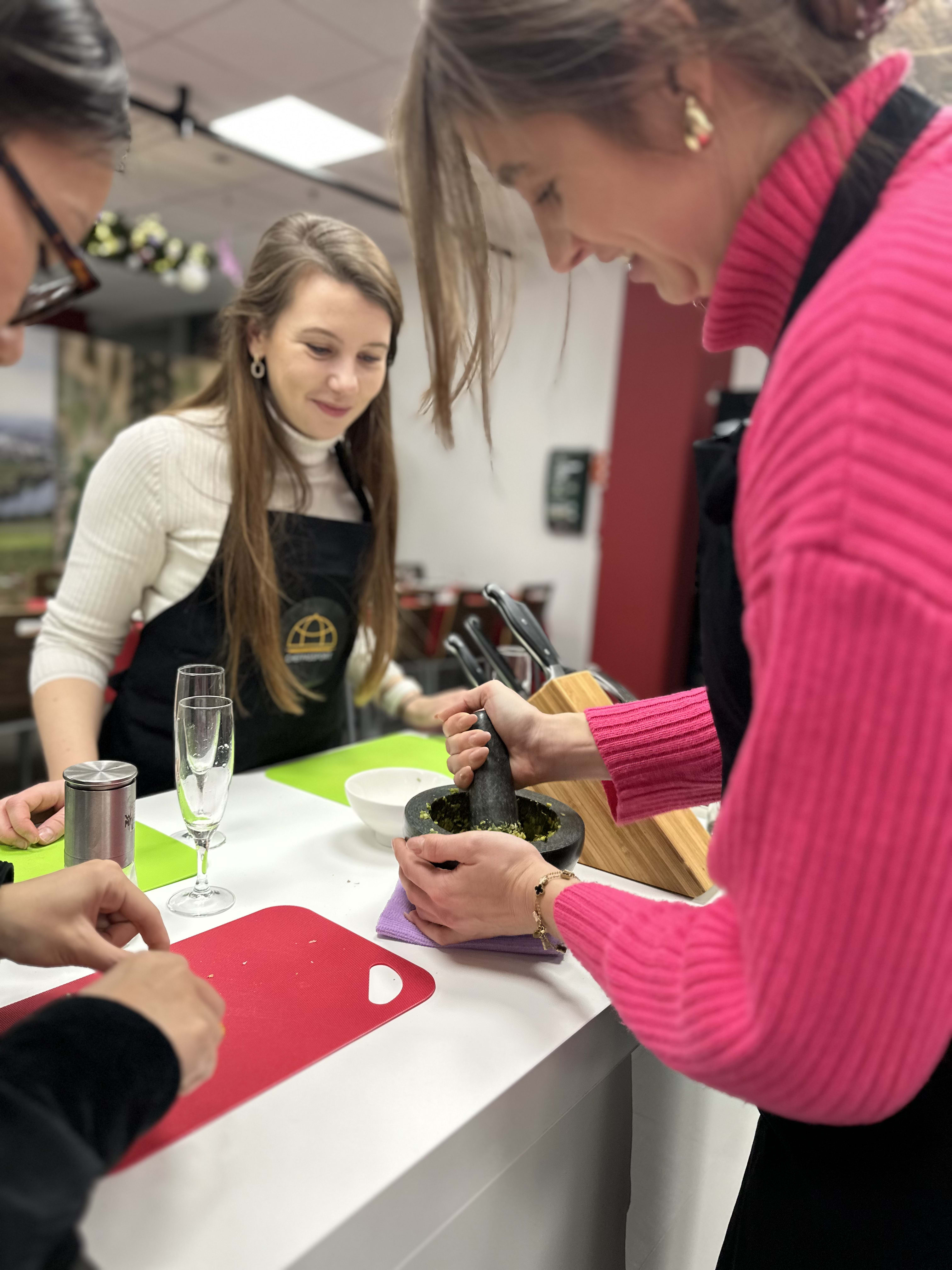 Women in cooking class using mortar and pestle to grind ingredients together