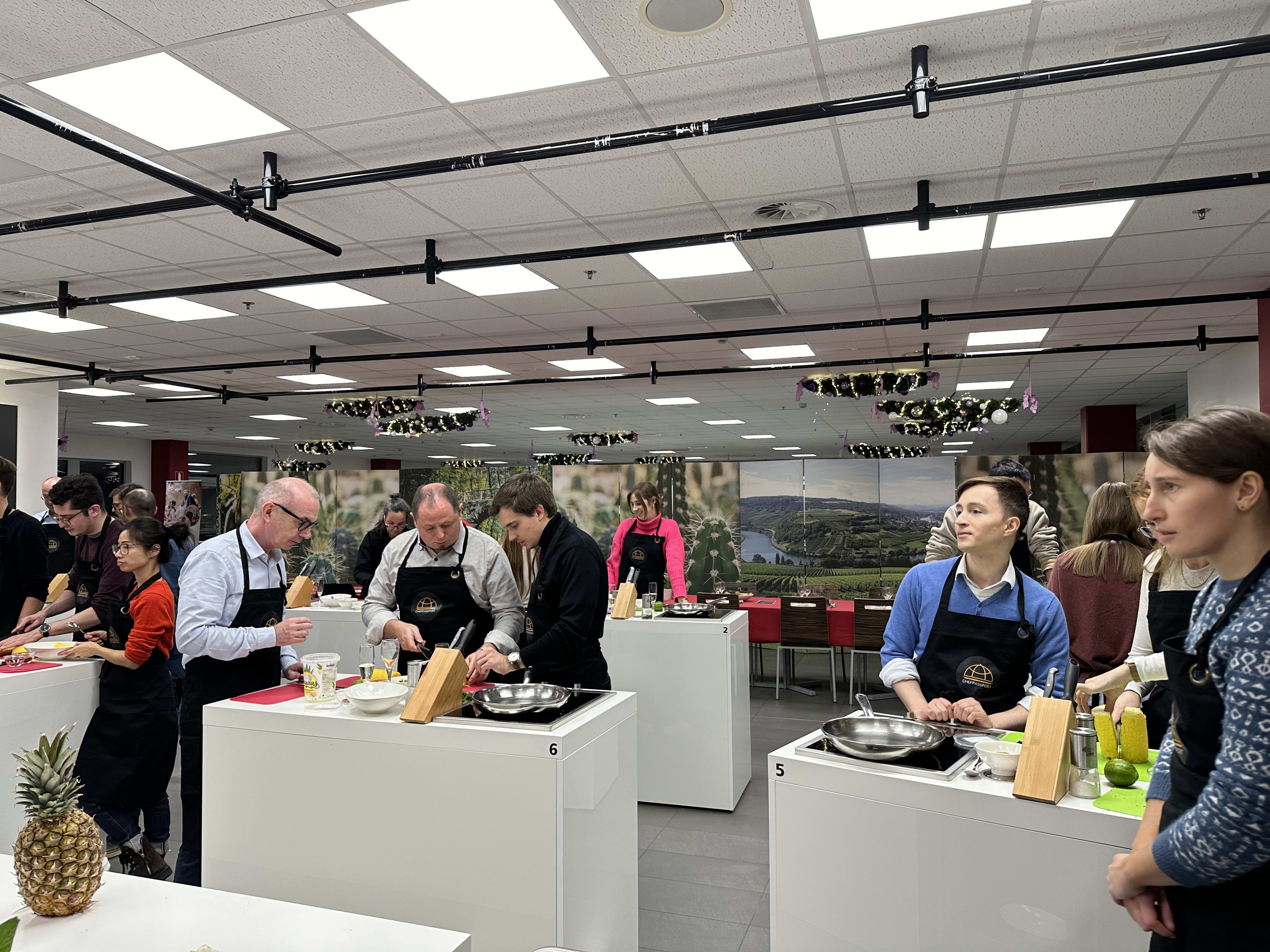 People in black aprons cooking at individual stations during a culinary class or competition