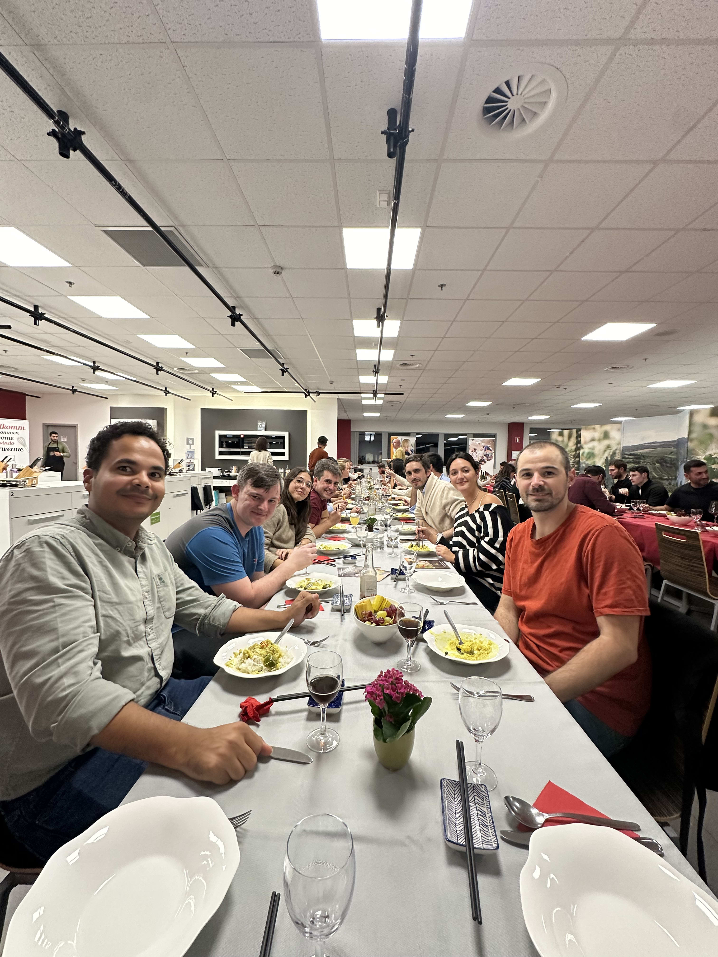 Group of coworkers enjoying a meal together at a long table in an office setting