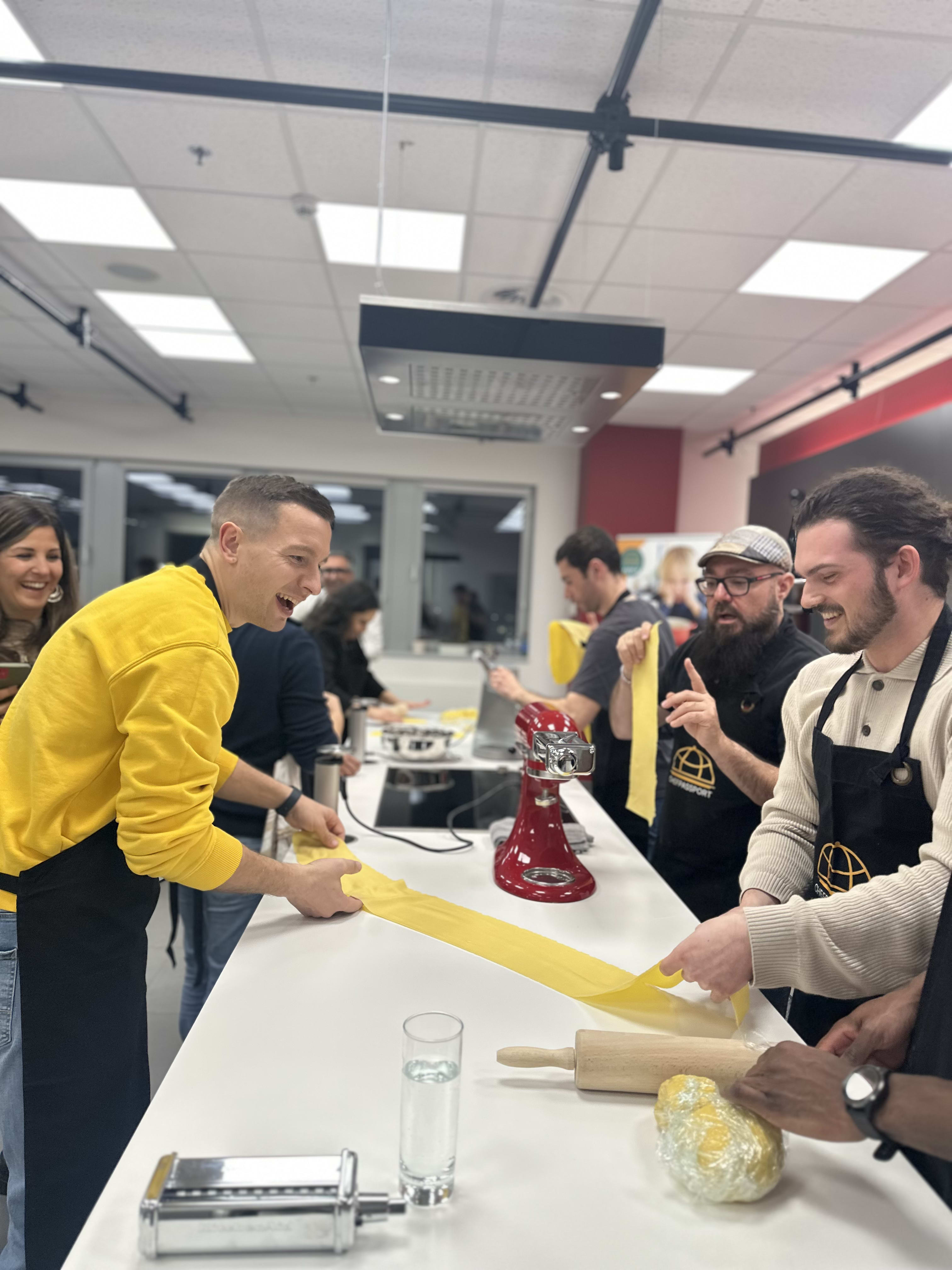 People in aprons making pasta together at a cooking class in a modern kitchen