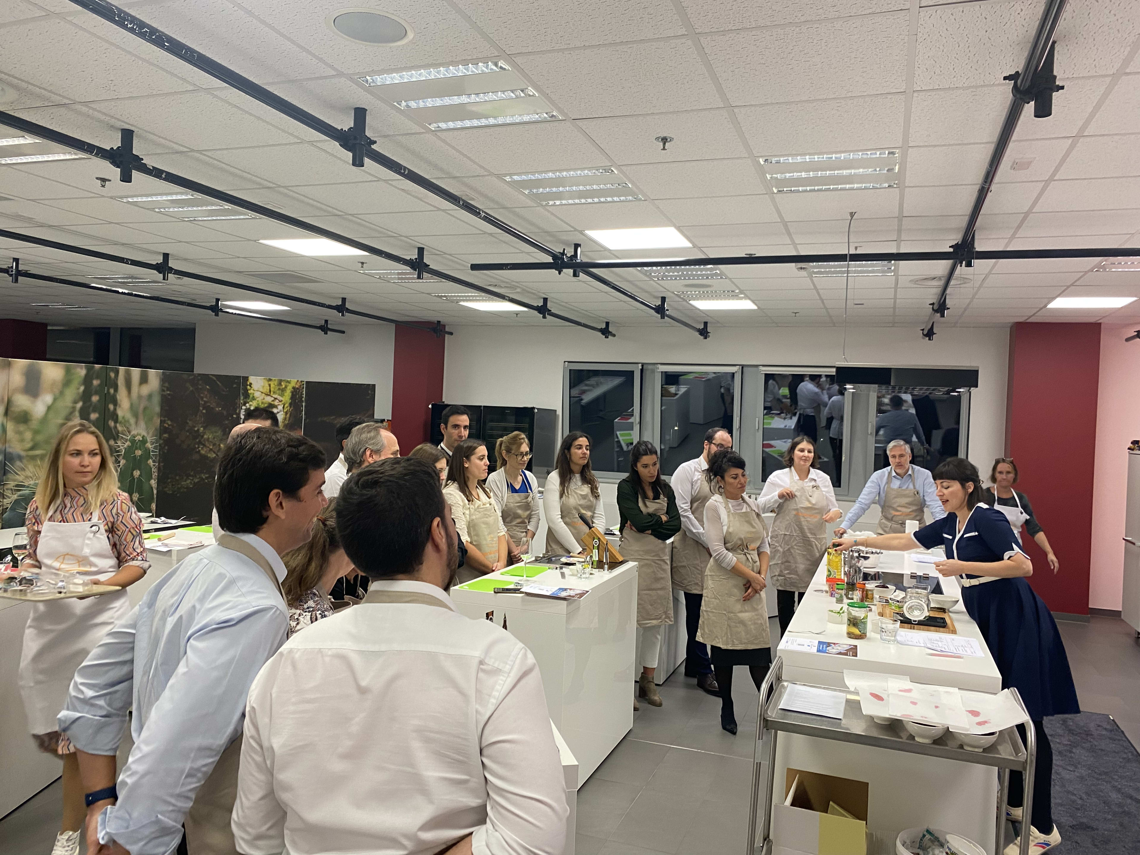 Group of people in aprons attending a cooking class in a modern kitchen studio