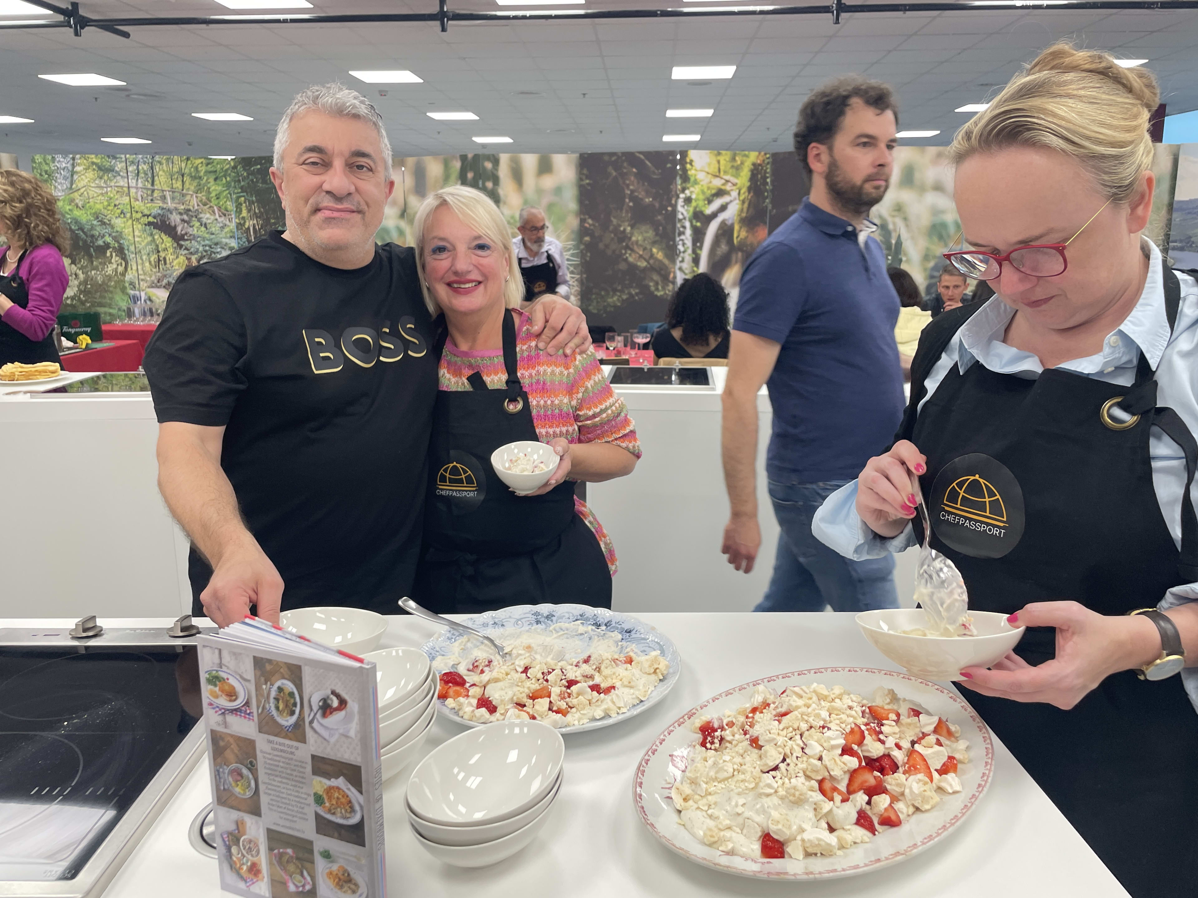 People in Chef Passport aprons serving strawberry dessert at culinary event