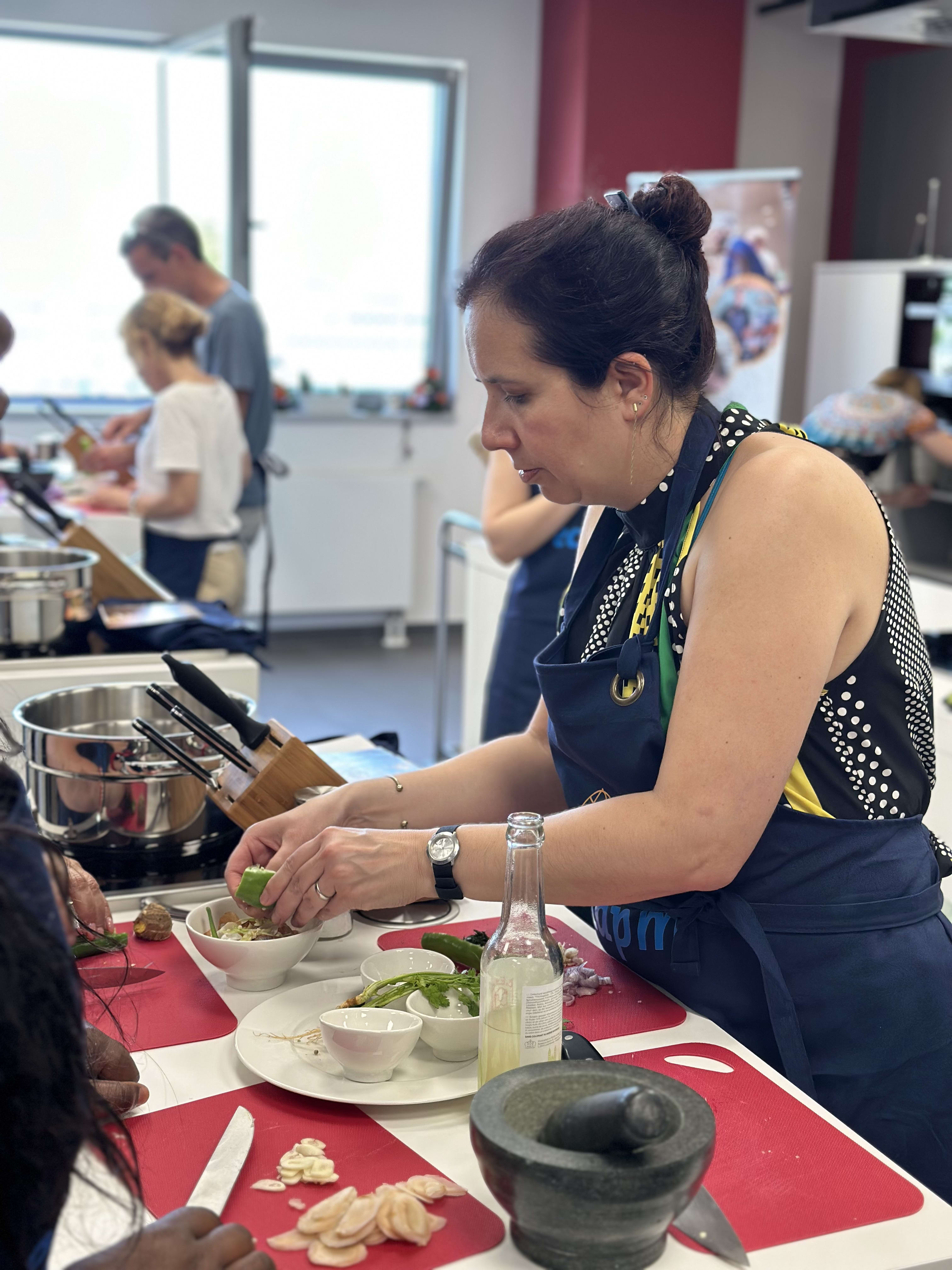 Woman in navy apron preparing food with lime and bowls at cooking class workstation