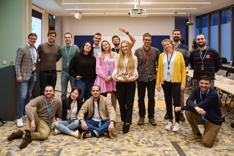 Corporate team building group photo with participants holding food platter in modern office