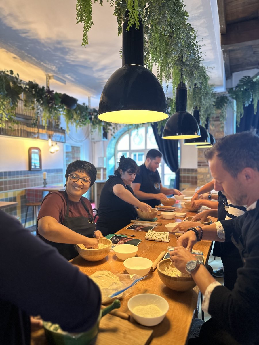Group of people participating in a cooking class at a table with bowls and ingredients