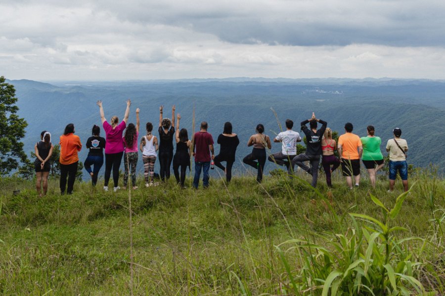 A diverse group enjoys a serene mountain view, practicing yoga outdoors together.