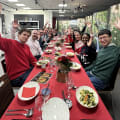Large corporate team celebrating at festive holiday dinner with raised hands