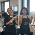 Diverse cooking class participants wearing aprons smiling at tables in bright Luxembourg venue