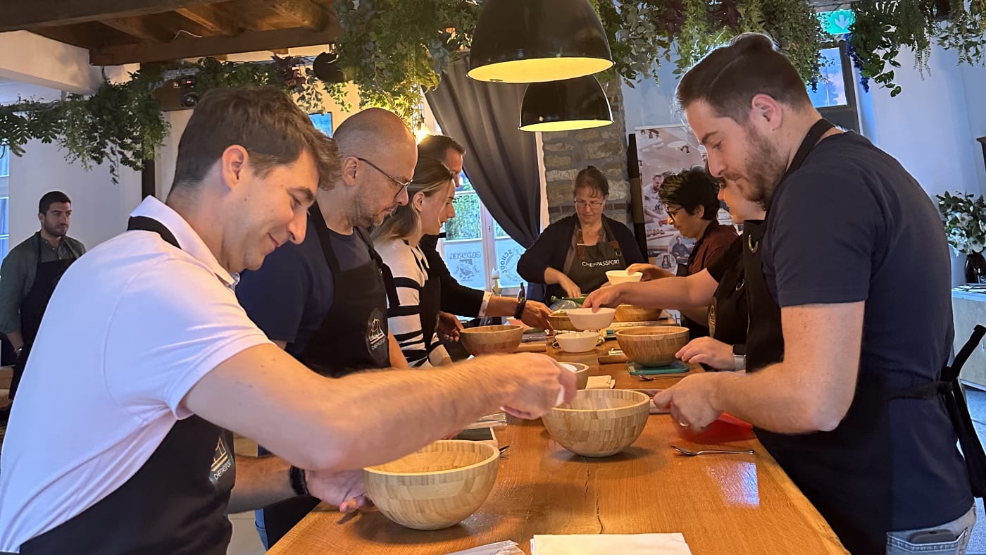 Group of people participating in a cooking class at a wooden table with mixing bowls