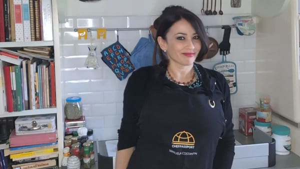 Chef Manuela Costantin in black chef coat standing in her kitchen