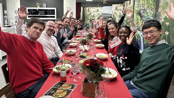 Large corporate team celebrating at festive holiday dinner with raised hands