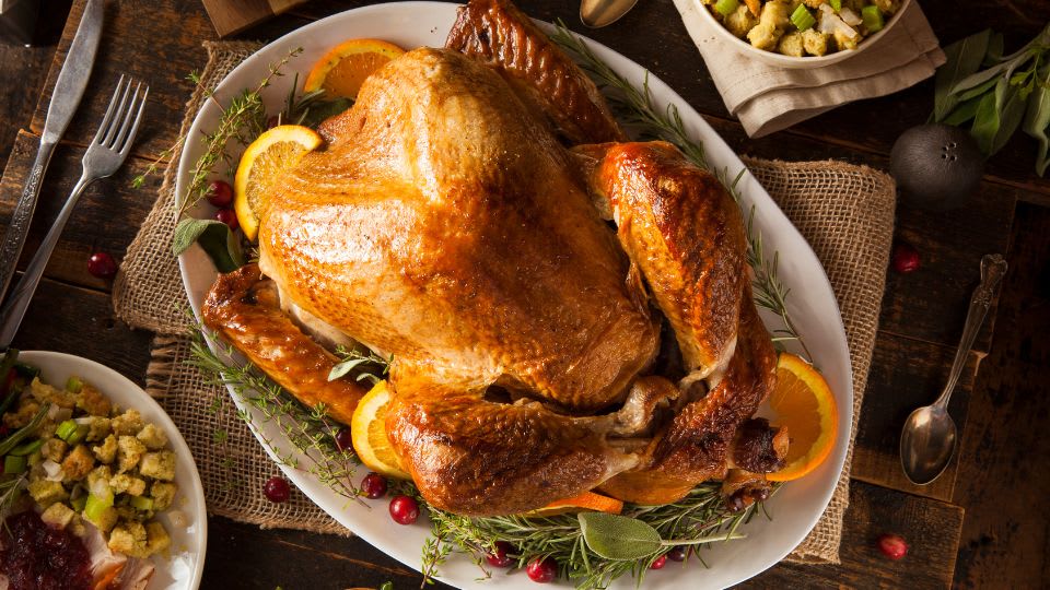 Golden brown roasted Thanksgiving turkey on serving platter with fresh herbs