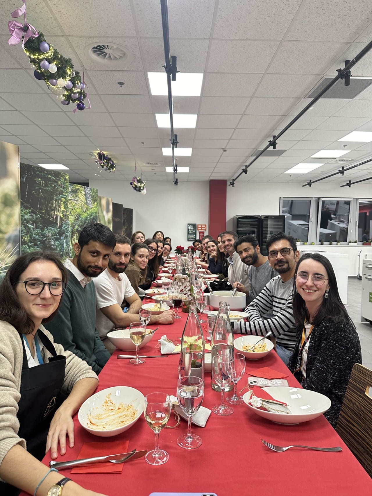 Corporate team dining together at long red table after cooking class celebration