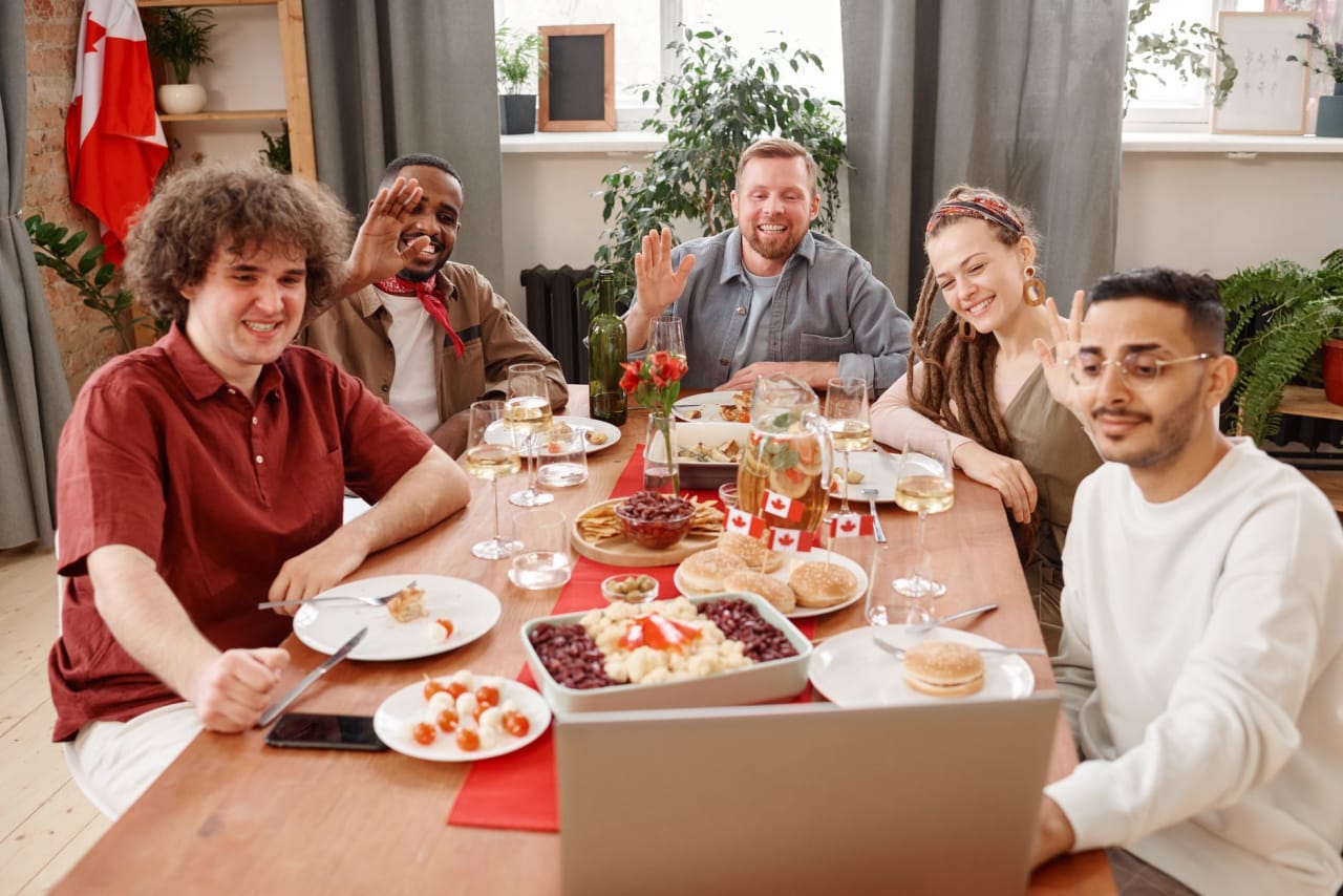 A group of friends sharing a joyful meal and engaging in a video call. Diverse, happy scene.