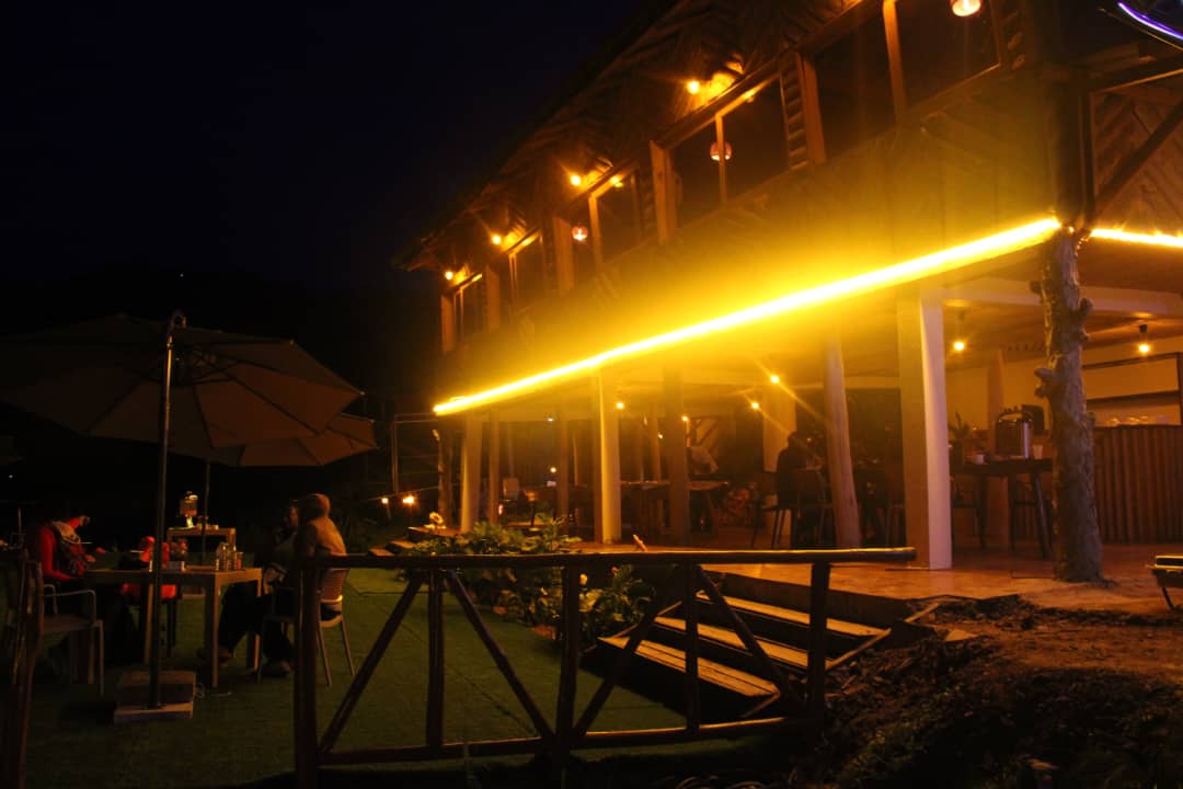 Nighttime front view of Bunyonyi Luxury Resort with glowing lights reflecting beautifully on Lake Bunyonyi.