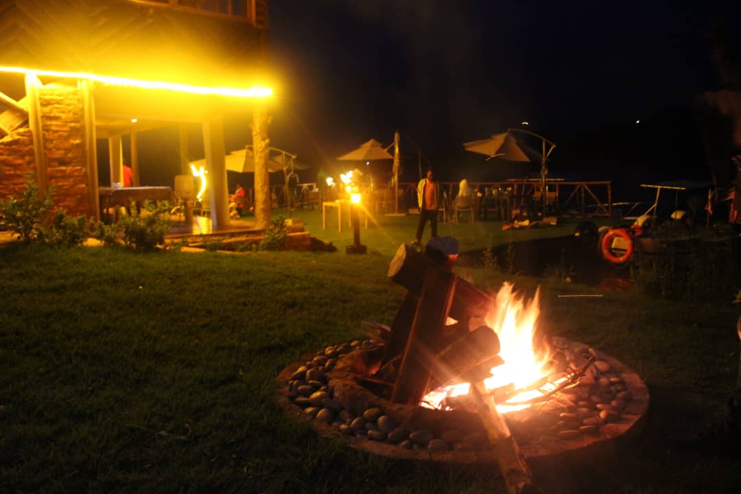 Guests enjoying a warm night campfire with a cold Lake Bunyonyi ambience at Bunyonyi Luxury Resort.