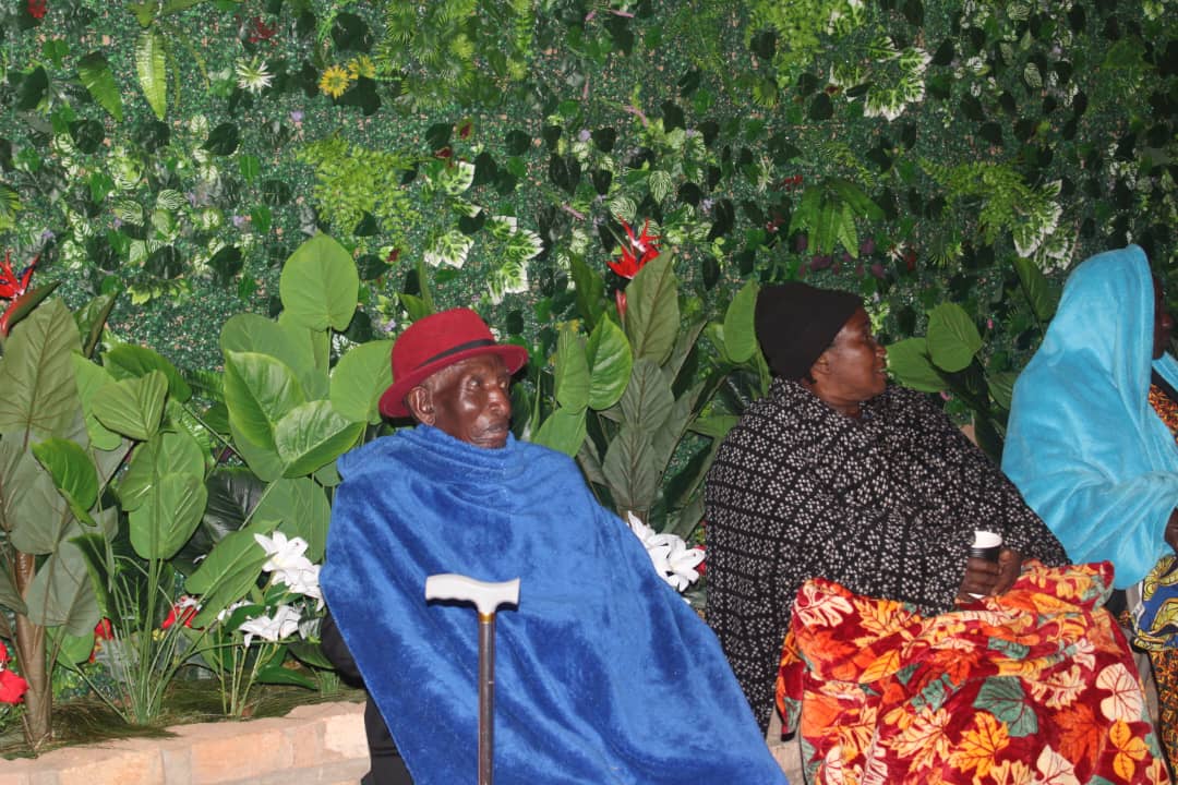 Guests seated in front of Bunyonyi Luxury Resort with the lush artificial green forest in the background.