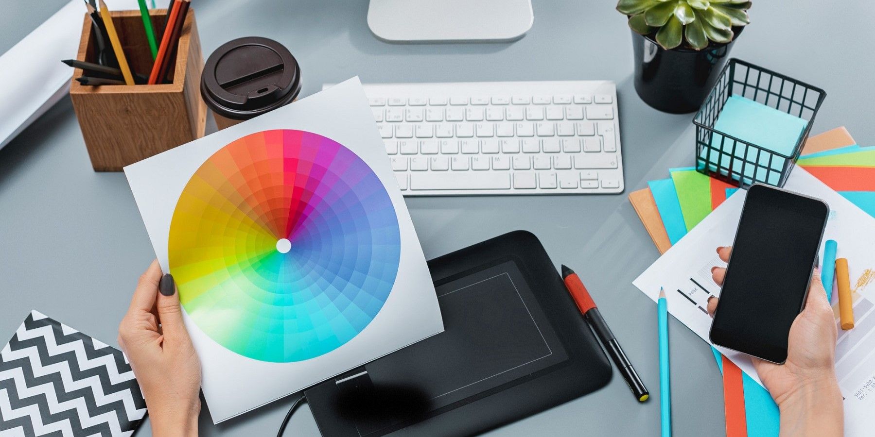 the-gray-desk-with-laptop-notepad-with-blank-sheet-pot-of-flower-stylus-and-tablet-for-retouching.jpg