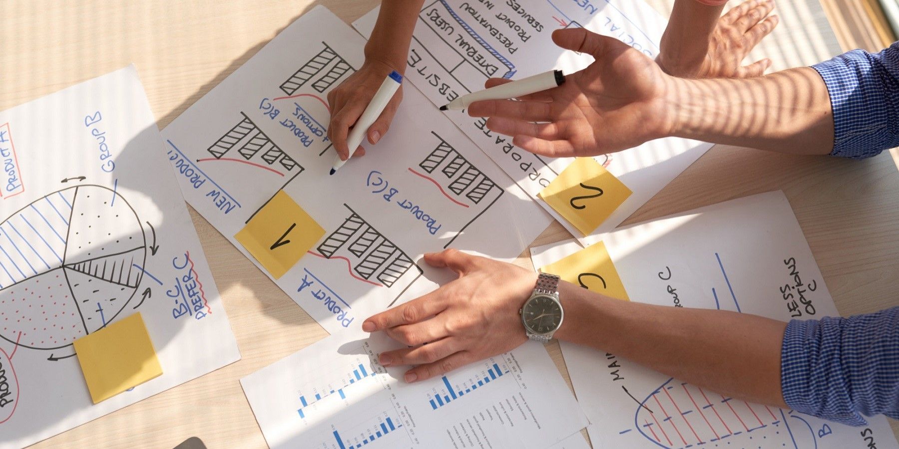 top-view-of-creative-team-discussing-business-graphs-drawn-in-marker-pens.jpg