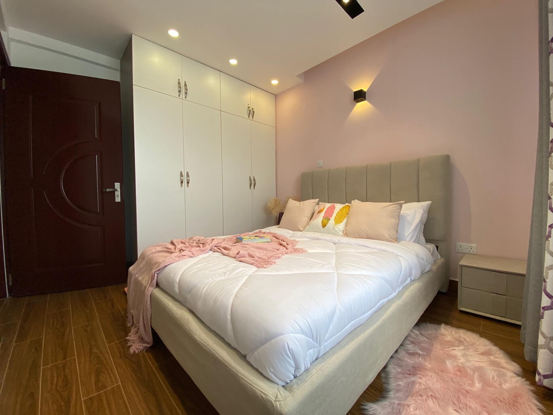 a fully furnished bedroom with pink walls