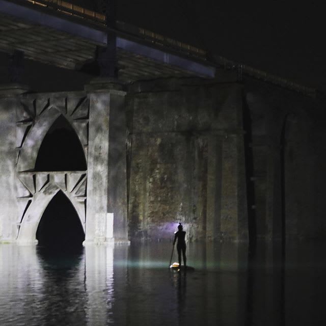 stand up paddle by night lighting a bridge