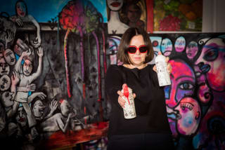 Iwona Siwek-Front holding painted spray cans in front of her work