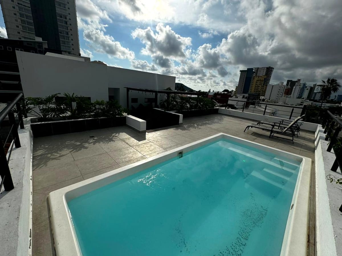 Rooftop pool and sun loungers with the city and ocean in view